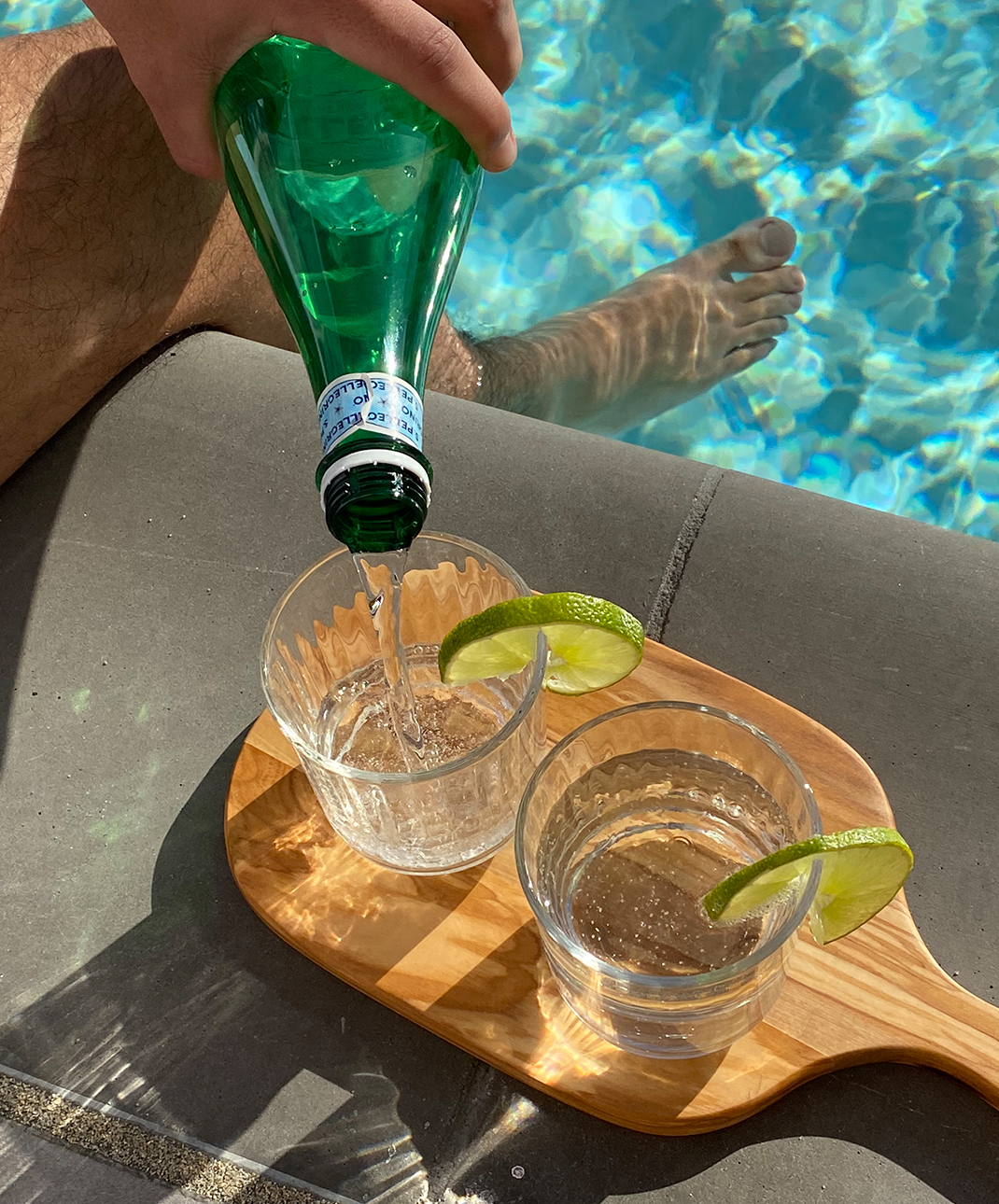 Two glasses of sparkling water next to a pool