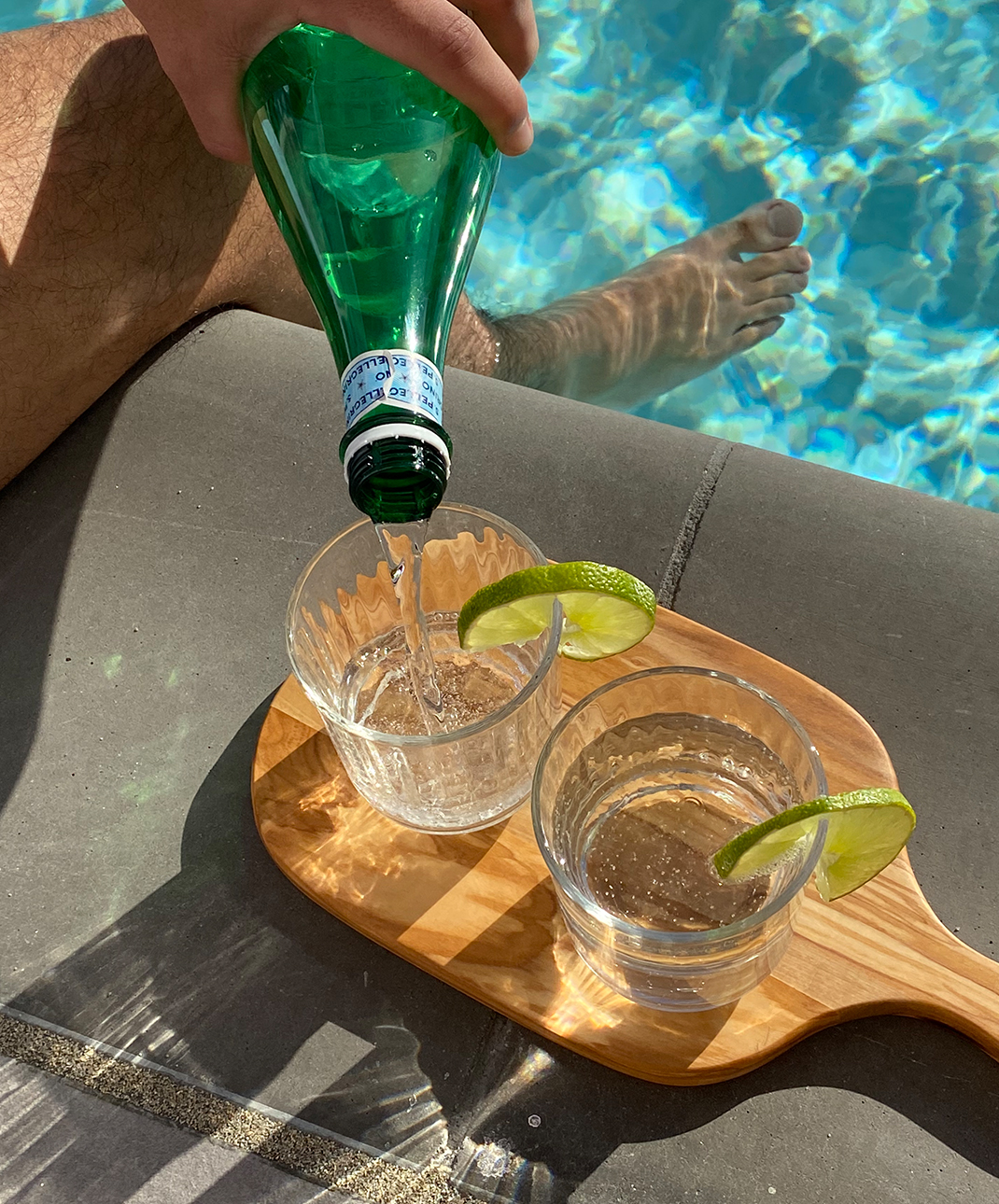 Two glasses of sparkling water next to a swimming pool